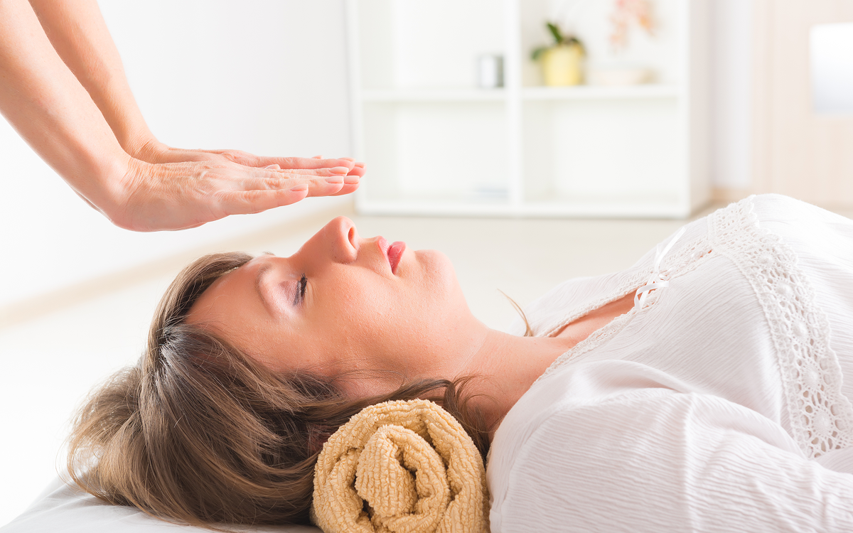 Woman receiving reiki treatment, lying down relaxed.
