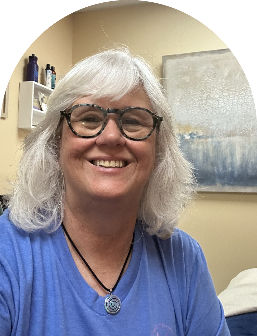 Smiling person with glasses and white hair.